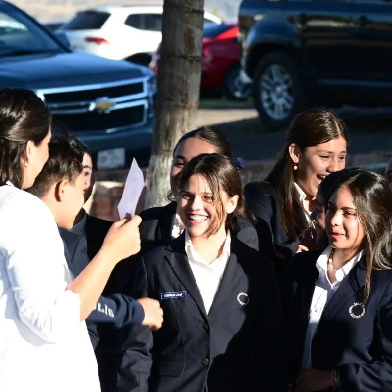 Estudiantes del instituto en uniforme realizan actividad grupal en estacionamiento durante evento escolar